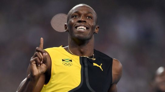 Three-time champion: Usain Bolt celebrates winning the 100m final, with Justin Gatlin, right, finishing second.