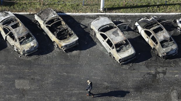 A man walks past a row of gutted cars at a dealership in Dellwood, Missouri, after rioting followed the grand jury's decision in the Michael Brown shooting case.