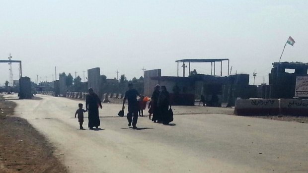 Shift: Residents flee Iraq's northern city of Mosul in July, walking towards nearby Erbil.