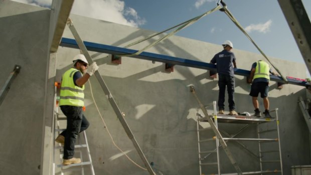 Workers pull together pre-fabricated building parts.