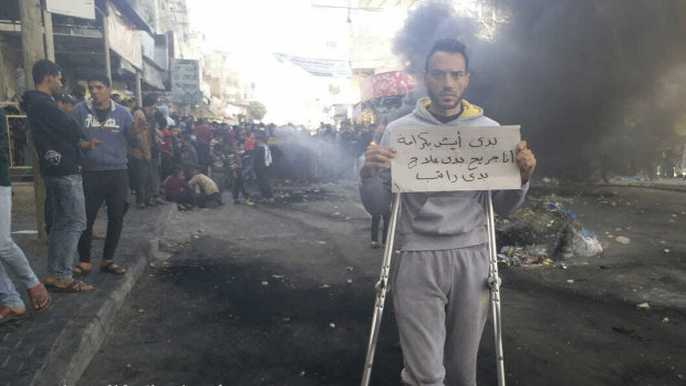 This photo provided by Palestinian journalist Osama al-Kahlout shows a protester holding a sign that reads in Arabic, "I want to live in dignity". Al-Kahlout was detained the next day.