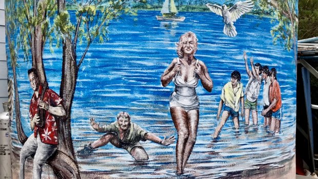 Simon White's mural on a water tank, imagining celebrities hanging out in Loch Sport. 