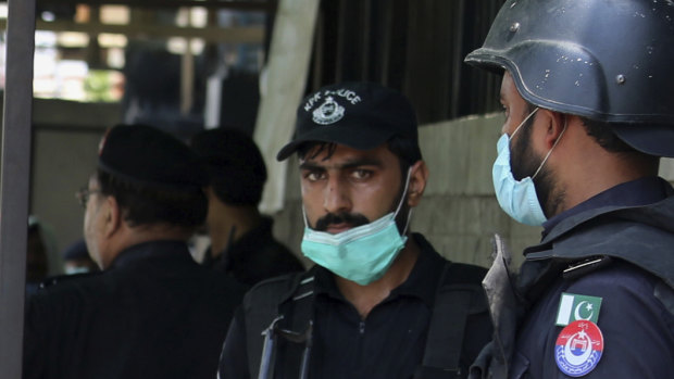 Police officers gather at an entry gate of a district court following the killing of Tahir Ahmed Naseem who was accused of insulting Islam, in Peshawar, Pakistan.