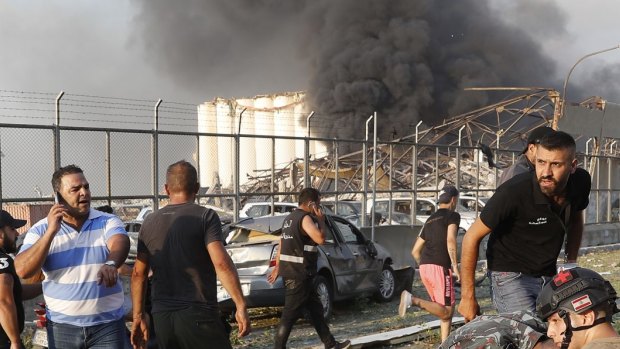 Rescue workers help an injured man at the explosion scene that hit the seaport of Beirut.