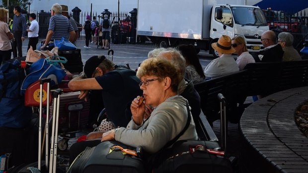 Passengers sit with their luggage after disembarking from the Ruby Princess cruise ship on March 19 at Circular Quay.