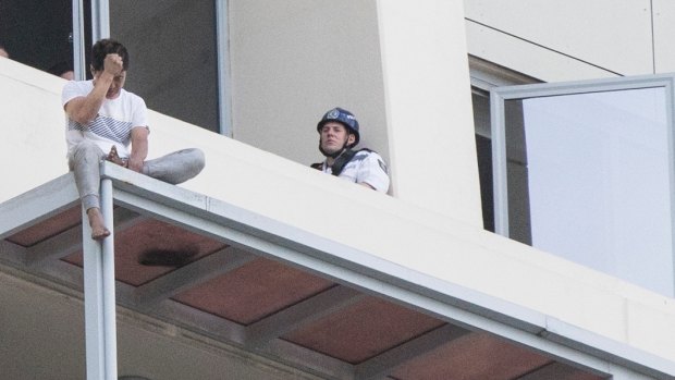Police speak to June Oh Seo on the awning of a Chatswood high-rise building. 
