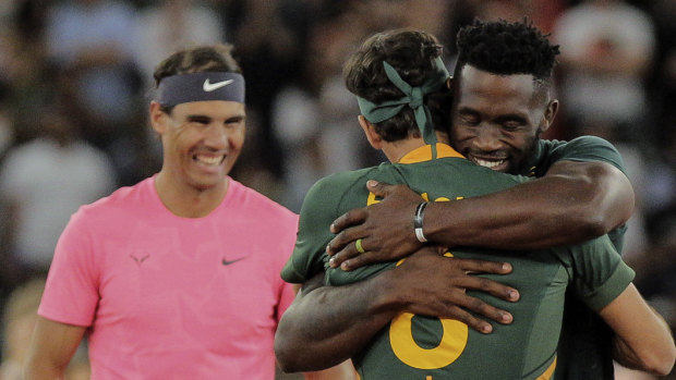 Siya Kolisi embraces Federer after presenting him with a Springboks rugby jersey.