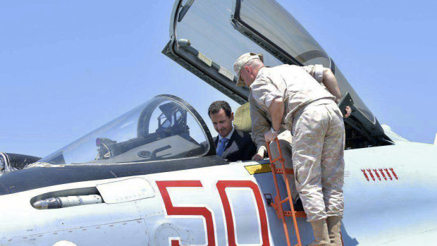Syrian President Bashar Assad climbs into the cockpit of a Russian SU-35 fighter jet as he inspects the Russian Hmeimim air base in the province of Latakia, Syria in 2017. 
