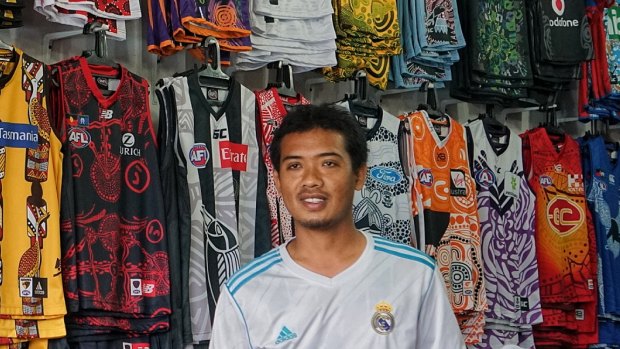 Muhammad Bakri in his shop in Kuta selling knock off AFL shirts and decorated helmets.