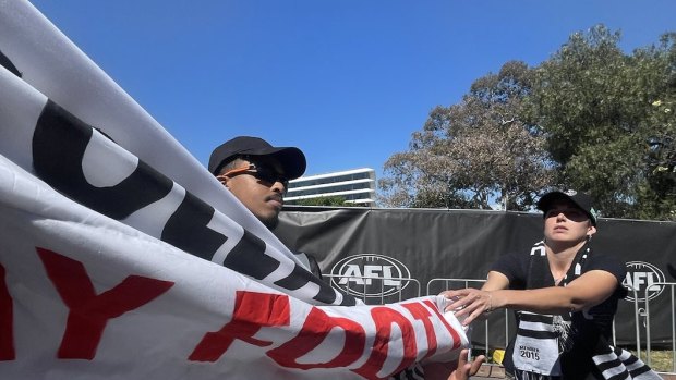 Protesters glue themselves to road during grand final day parade