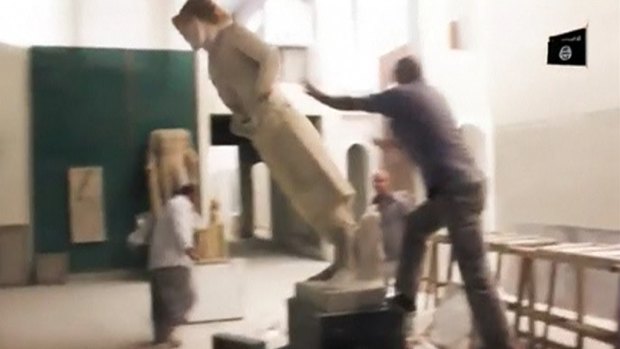 A man pushes a statue in a museum in Mosul in a still image taken from an undated video. 