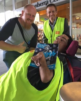 Greens MLA Shane Rattenbury sells The Big Issue with vendor Tau (right) while getting the thumbs up from a prospective customer.