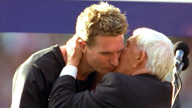 James Hird is hugged by Lou Richards on the podium after being awarded the Norm Smith medal after Essendon's 2000 grand final win.