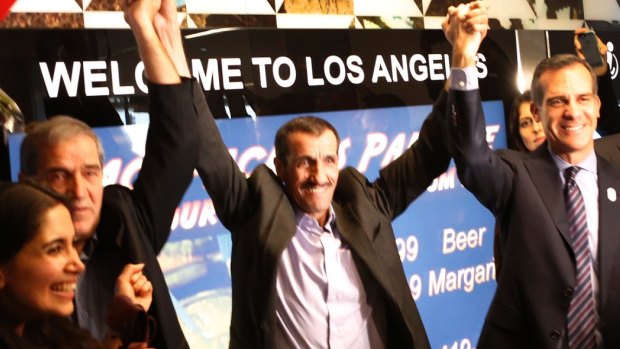 Ali Vayeghan, an Iranian citizen with a valid US visa, lifts his arms with his brother Houssein and Los Angeles mayor Eric Garcetti.