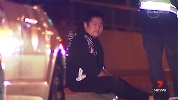 Kevin Pua sits beside the road where his sister Carmen fell from his car, suffering fatal head injuries.
