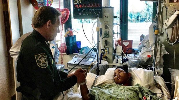 Sheriff Scott Israel, holding the hand of Anthony Borges, 15, a student at Marjory Stoneman Douglas High School. The teenager was shot five times.
