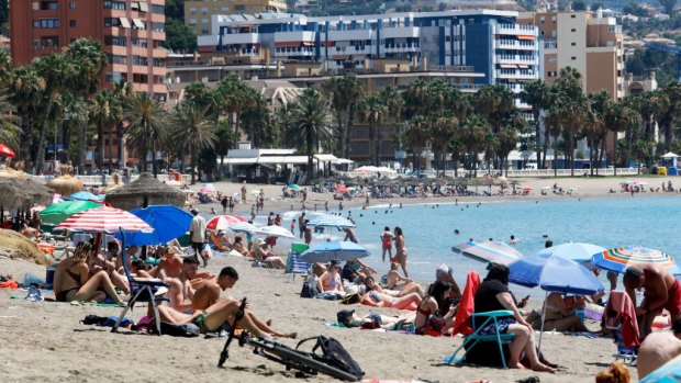 Sunbathers enjoy along the beach of Malaga, Andalucia, Spain. 