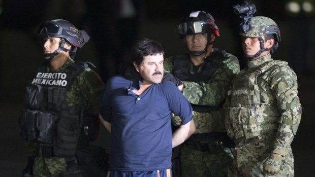 Joaquin "El Chapo" Guzman is made to face the press as he is escorted to a helicopter in handcuffs by Mexican soldiers and marines at a federal hangar in Mexico City on Friday.