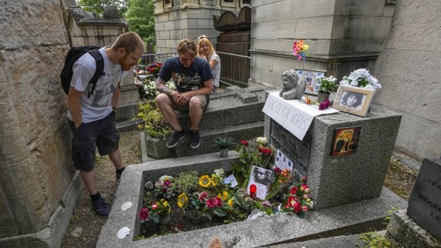 Joachim Tittmar from Germany, left, Walter Homburg of the Netherlands, centere and his girlfriend Kate Schirm gather at the tomb of rock singer Jim Morrison.