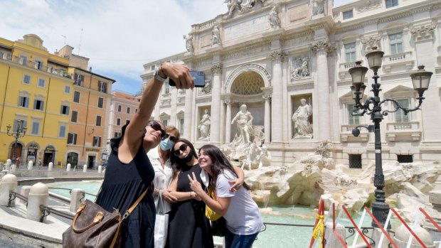 People take selfies in front of Trevi Fountain. 