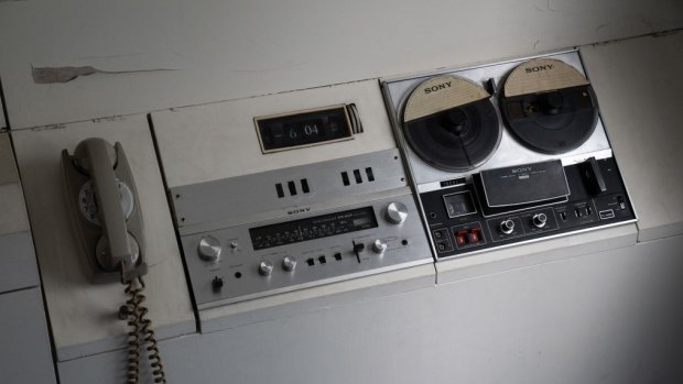 An original telephone, tape recorder and radio are pictured in a capsule room.