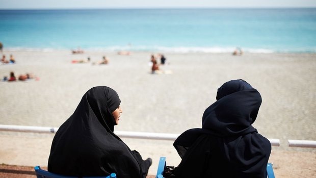 Muslim women watch sunbathers on the beach in Nice, France.