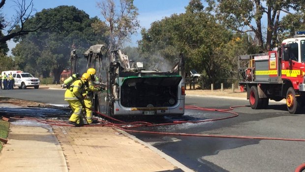 Firefighters attend to the burnt out bus.