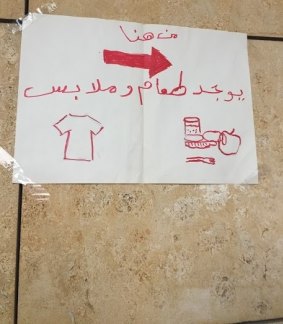 A sign directing migrants to clothing and food.