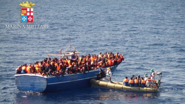 A handout picture from the Italian navy shows a boat full of migrants being picked up off the coast of Sicily.