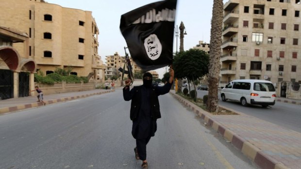 A member of the Islamic State in Iraq waves an ISIL flag.