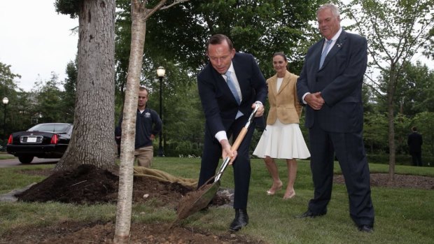 Climate-change-denying Prime Minister Tony Abbott plants a tree at the Australian embassy in Washington with ambassador Kim Beazley and his wife Susie Anus.