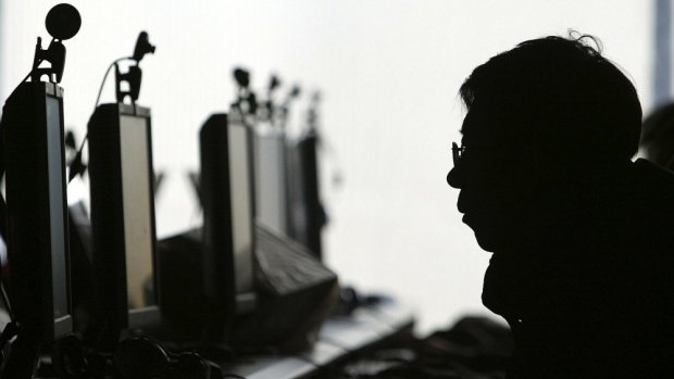 A computer user is silhouetted with a row of monitors at an Internet cafe in Shenyang, in northern China's Liaoning province.
