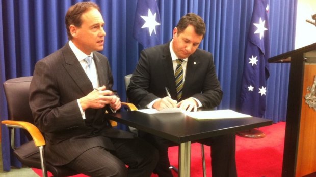 Federal Environment Minister Greg Hunt watches as Queensland counterpart Andrew Powell signs the $40 million Reef Trust in Brisbane.