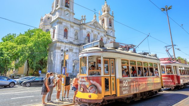 The historic Tram 28 in front of baroque and neoclassical Estrela Basilica in Lisbon.