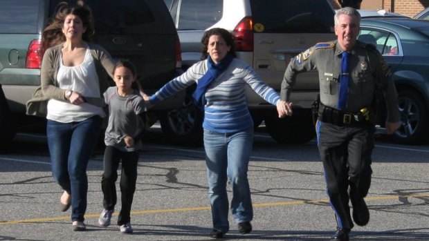 A police officer leads two women and a child from Sandy Hook Elementary School in Newtown, Connecticut, where a gunman opened fire, killing 26 people, including 20 children.