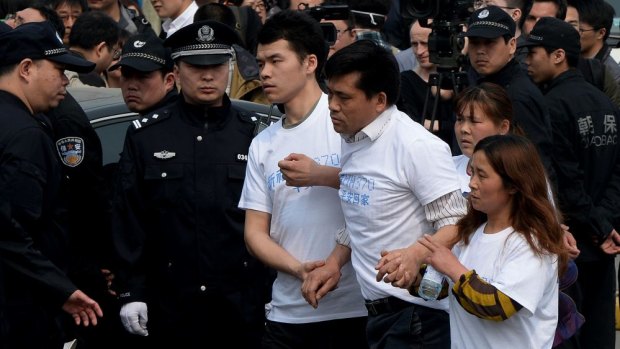 Grieving Chinese relatives of passengers on missing Malaysia Airlines flight MH370 walk past a police barricade as they gather to protest outside the Malaysian embassy in Beijing.