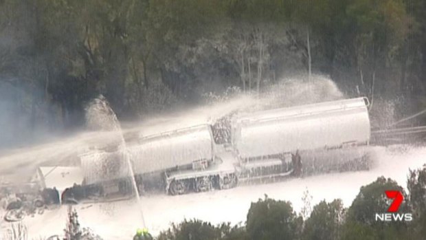 Crews from Fire and Rescue NSW spray foam on a tanker filled with ethanol.