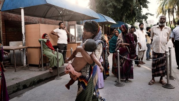 A mother enters ICDDR,B with her child. The facility treats 220,000 patients a year.
