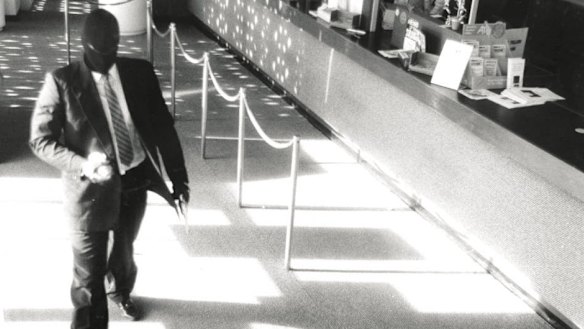 Hugo Rich robbing a bank in his ski mask.