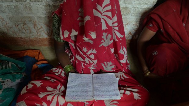 Grief: The mother of one of the victims of a gang-rape in Uttar Pradesh holds a schoolbook that belonged to her daughter.