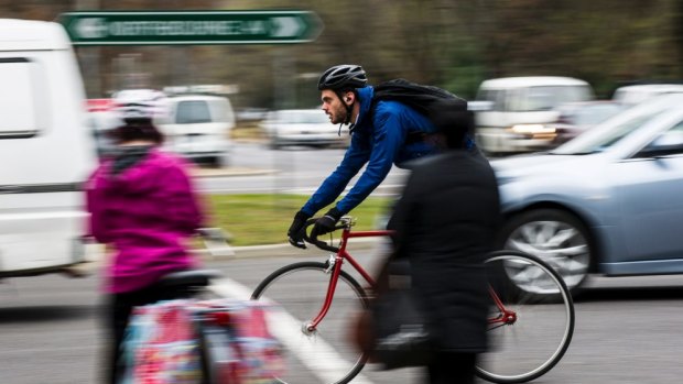 A cyclist travels down Northbourne Avenue in Braddon in peak-hour traffic.