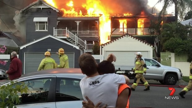 Friends console themselves after the fire destroyed two homes in Paddington.