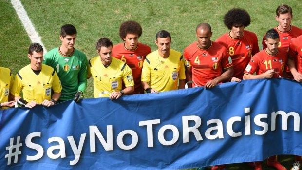 Belgium and Argentine players and referees pose with a "Say No to Racism" banner during a quarter-final football match.