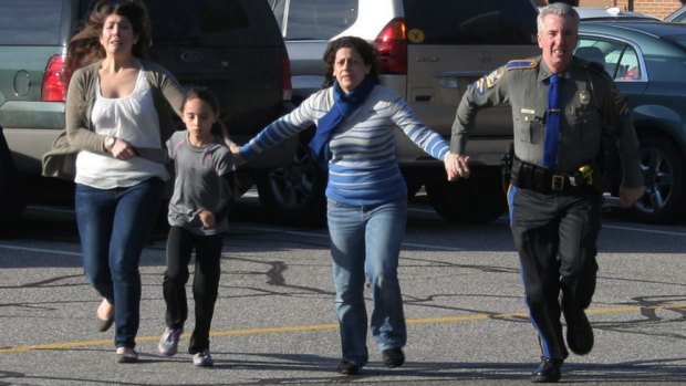 Running to safety: A police officer leads two women and a child from Sandy Hook Elementary School in Newtown, Connecticut, during the massacre. 