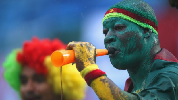 A Cameroon fan blows a horn in the rain at the match between Mexico and Cameroon at Estadio das Dunas in Natal, Brazil.