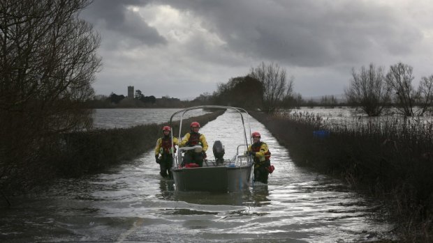 Members of Devon and Somerset Fire and Rescue Service crew a  boat along the main road leading to the village of Muchelney.