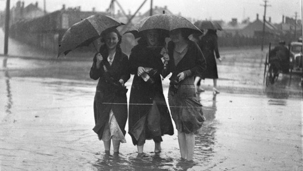 An archive photograph from the NSW State Library shows people crossing a flooded street in Alexandria.