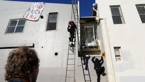 Protestors scale one of the buildings set to be redeveloped  in Redfern at 'The Block'.