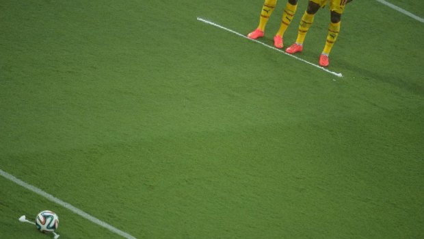Cameroon's players stand behind a line marked by a free-kick marker spray.