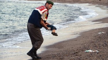 A police officer carries the dead migrant child after he washed up on a beach near the Turkish resort of Bodrum.